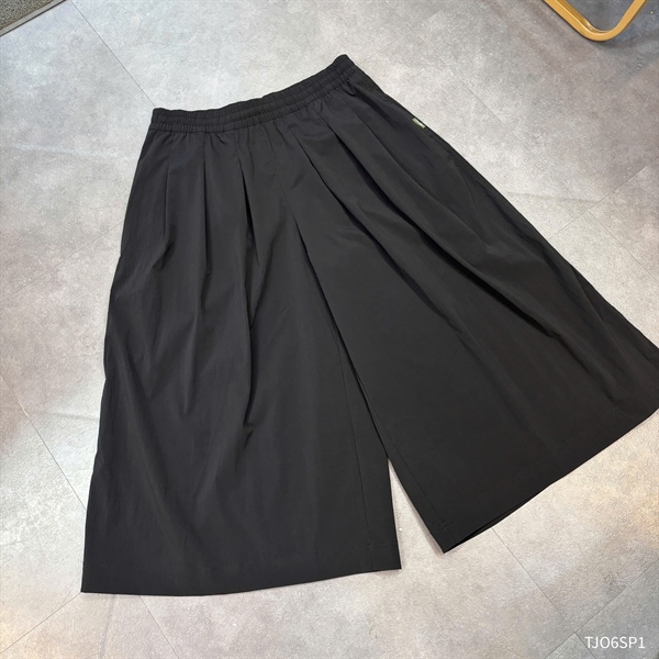Quần culottes ống rộng nữ màu đen, cạp chun, xếp ly trước, trải phẳng trên sàn xám