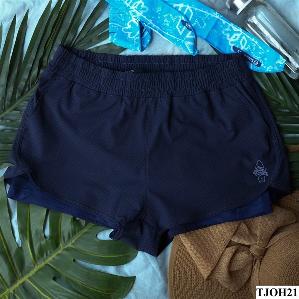 Quần short nữ xanh navy hai lớp, cạp chun, lớp trong xanh đậm, trải phẳng cùng lá cọ, khăn xanh và mũ cói